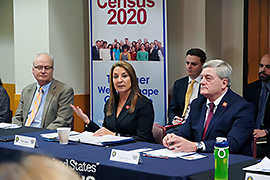 Secretary Hughs sitting at a table with other officials.