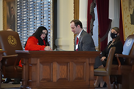 Secretary Hughs is sitting with two other individuals while the counting of the ballots is taking place.