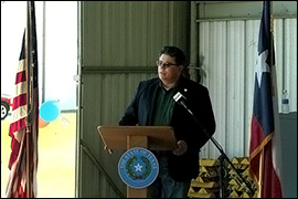 Secretary Pablos standing at a podium in a metal warehouse. 
