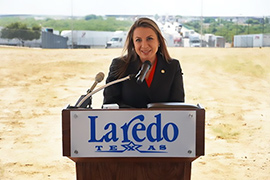 Secretary Hughs standing behind a podium that has a Laredo sign. 