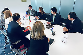 Secretary Hughs sitting at a coference table with officials. Everyone looks enganged. 