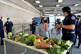 La secretaria y un persona hablando en frente de un mesa con fruita.