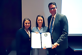 Secretary Hughs presenting a certificate to two American Airlines representatives. 